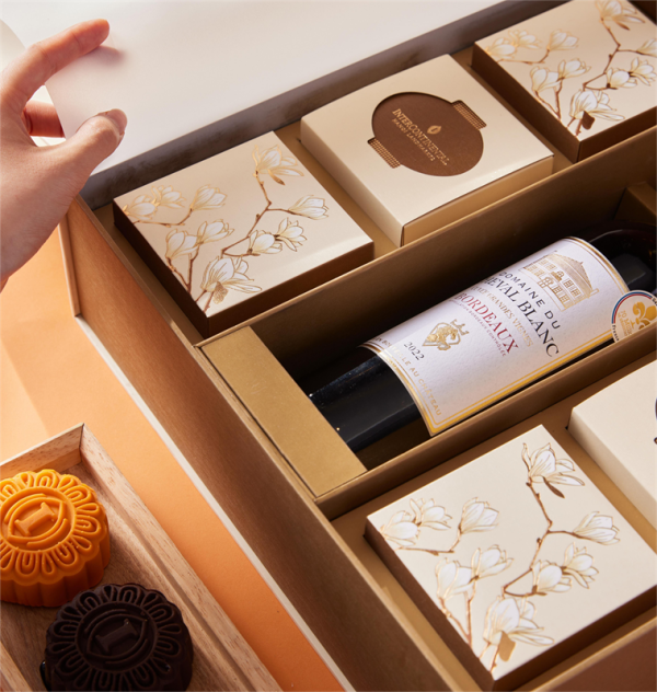 Hộp bánh Trung Thu cao cấp từ InterContinental với thiết kế hoa magnolia và rượu vang Pháp Domaine du Cheval Blanc, đi kèm bánh nướng sang trọng.